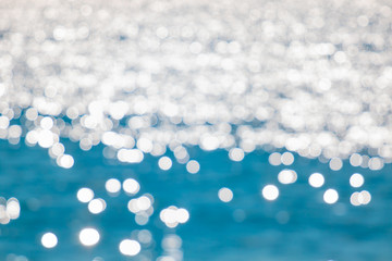 Abstract blurred blue water with shining sunlight bokeh on blue sea