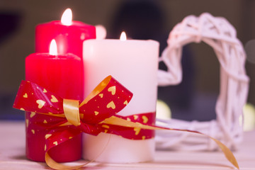 The concept of Love, Wedding, Proposal, Anniversary. A romantic evening with three burning red and white candles. Dark blurred background