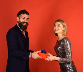 Beautiful young couple celebrating at home on red background.