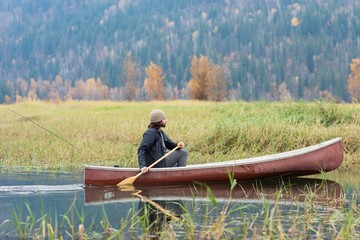 Man oaring canoe in river