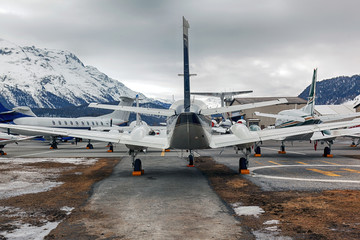 Fototapeta na wymiar Rear view of private jets, planes and helicopters in the airport of StMoritz Engadin Switzerland in the alps