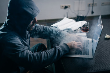 criminal mysterious man hacking laptop, in the dark, smoke
