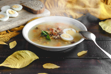 Healthy and warming winter soup with rice, chickpeas, chicken, ham and boiled egg over rustic wooden table background. Spanish soup (Puchero Andaluz). Winter food concept