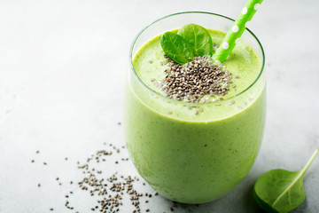 Vegetarian healthy green smoothie from avocado, spinach leaves, apple and chia seeds on gray concrete background. Selective focus. Space for text.