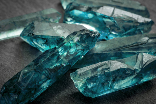 Aquamarines  and raw crystal gems concept with closeup of a bunch of blue uncut aquamarine, topaz or tourmaline crystals
