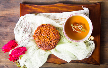 Chinese mooncake and tea with rose served on wooden saucer