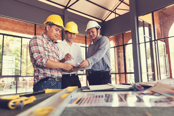 three construction engineers working in construction site with blueprint