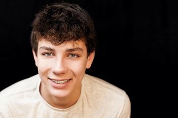 A guy with braces on his teeth in a white T-shirt on a black background