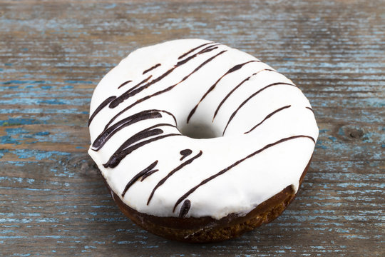 white glazed donut with chocolate stripes on wooden background