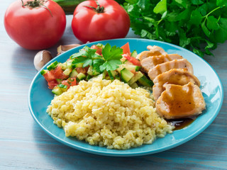 Turkey meat, fried with teriyaki sauce, cucumber salad .tomato, vegetables, a side dish of bulgur, side view