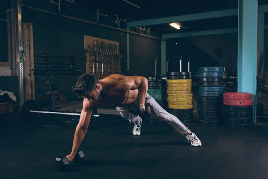 Muscular man doing push-up with dumbbells