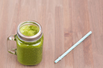 A green smoothie in a mason jar with tube
