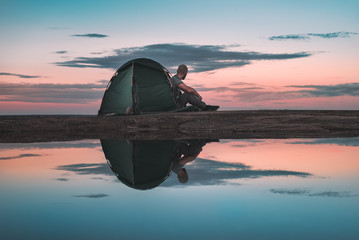 reflection in the water, man in the tent, sunset background