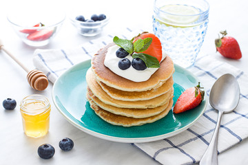 Stack of pancakes on the plate. Morning breakfast with berries on the table. Close up
