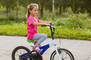 Naklejka premium little girl riding bicycle in city park.