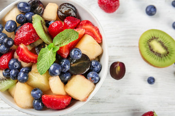 Bowl with delicious fruit salad on wooden table