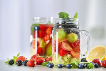Fototapeta na wymiar Mason jars of infused water with fruits and berries on table