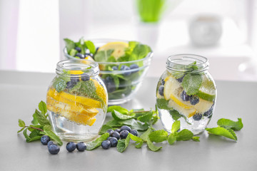 Jars of infused water and bowl with fruits on table