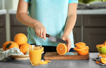 Woman cutting orange on board in kitchen