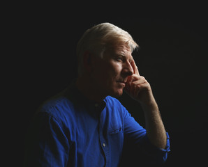Fototapeta na wymiar Portrait of thoughtful mature man on dark background