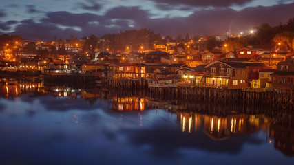 Fototapeta na wymiar Night image of the traditional wooden houses built on stilts (stilt houses) along the waters edge in Castro, Chiloe, Chile