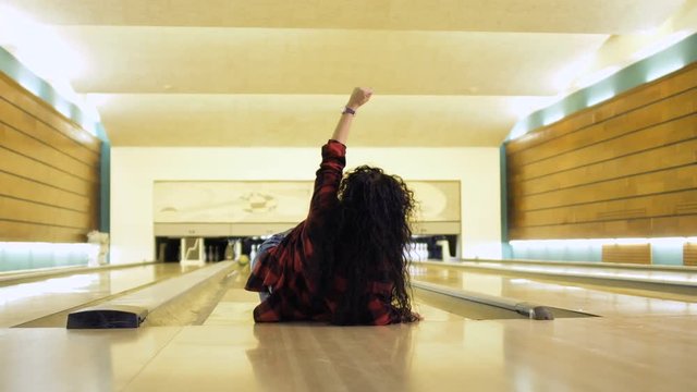 Young woman falls down while throws a bowling ball