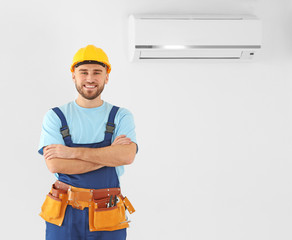 Male technician posing near air conditioner indoors