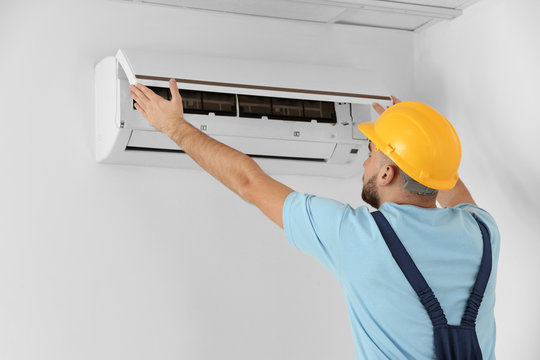 Male Technician Fixing Air Conditioner Indoors