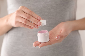 Young woman holding jar with hand cream, closeup