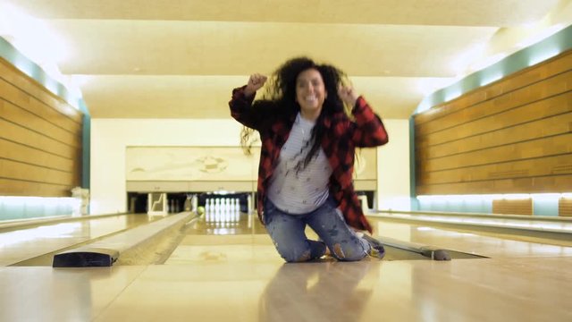 Young woman rejoices her failure during throwing bowling ball