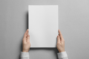 Woman holding blank sheet of paper on light background. Mock up for design