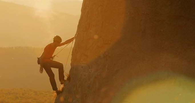 Climber climbing up the rock in amazing evening light.
