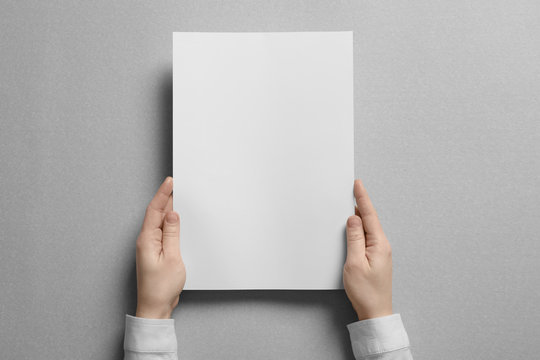 Woman Holding Blank Sheet Of Paper On Light Background. Mock Up For Design