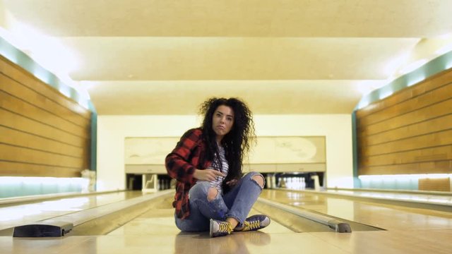 Young woman rejoices sitting at bowling alley