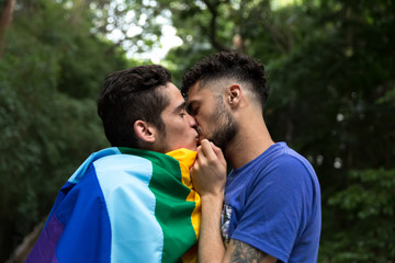Gay Couple Kissing with Rainbow Flag in the Park
