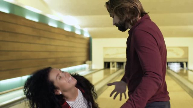 Man gives a heavy bowling ball to woman