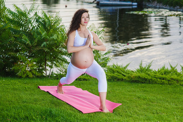 Pregnant woman doing prenatal yoga on nature.