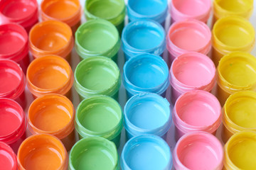Many open cans with bright colored paints.