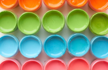 Many open cans with bright colored paints.