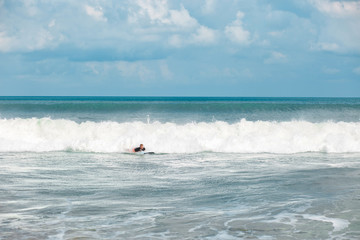 Young man moves through breaking waves in the ocean with his surf board and makes a lot of splashes