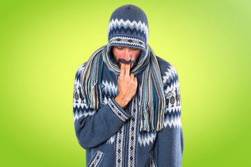 Man with winter clothes making vomiting gesture on colorful background