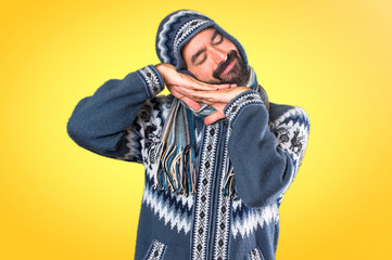 Man with winter clothes making sleep gesture on colorful background