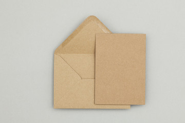 Blank brown kraft paper card and envelope on a grey background
