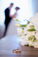 Wedding rings and bouquet on a background of blurred newlyweds