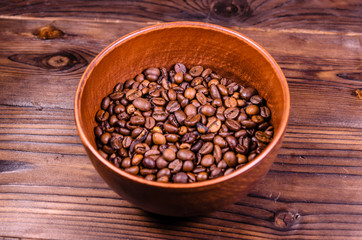 Roasted coffee beans in bowl on wooden table