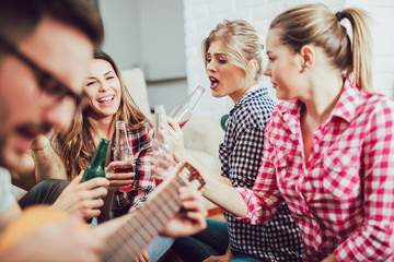 Group of happy young friends having fun and drinking beer in home interior