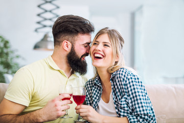 Photo of a young cheerful couple toasting at home with wine.