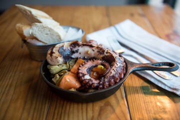 grilled octopus in a cast iron pan with vegetales