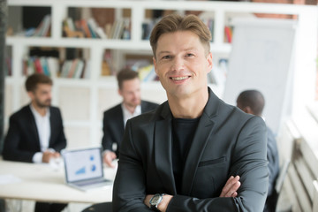 Smiling confident executive in suit standing with arms crossed looking at camera with business...