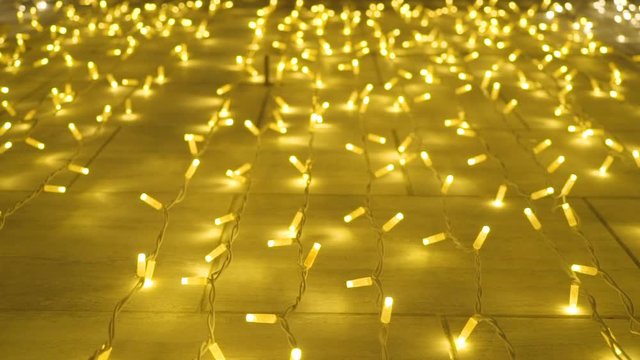 Many Christmas lights, yellow-colored, shining against the wall in a town.